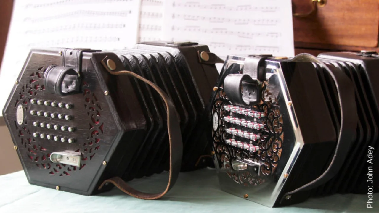 Two concertinas side by side with sheet music in the background.